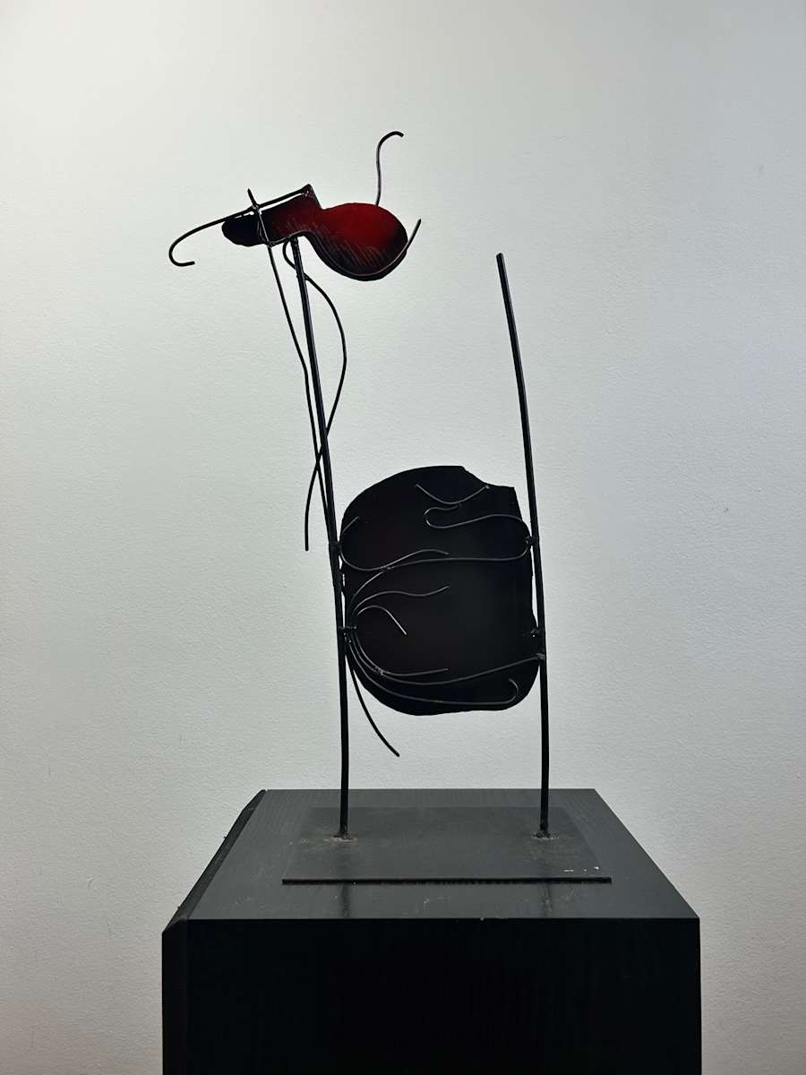 Untitled by Ruggero Gamberini  Image: An elegant interplay of balance and abstraction, this untitled 1999 sculpture by Ruggero Gamberini combines curved iron rods and sculpted sheet metal. The organic red form attached above the darker lower structure evokes a sense of suspended movement - perhaps a flower, a figure, an animal, or a poetic mechanism at rest. Gamberini blurs the line between lyrical gesture and mechanical form.