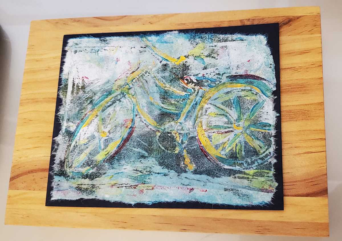 Bicycle Print by Jan Somers  Image: Using a linoleum block on a jelly plate this is a one of a mono print of a bicycle. The print is mounted on a wood block and has a place for hanging on the back
