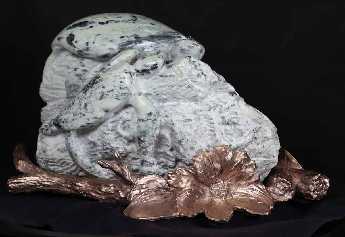 Turtles on a Log by Jan Somers  Image: Turtles carved in variegated soft green soapstone sitting on log the flowers, the bronze base created to complement the carving shows lily pads and water and flowers and logs.