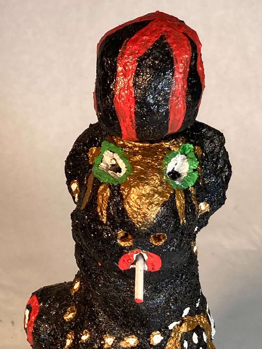 Black face with green eyes smoking and wearing black and red striped hat by Jennifer Taylor 