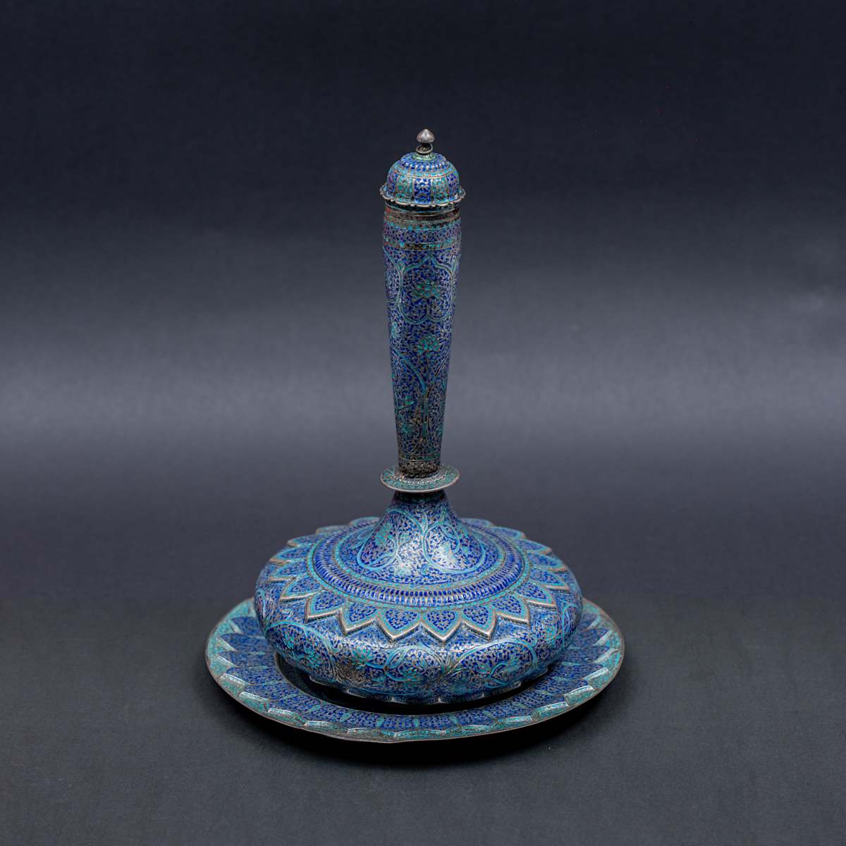 Enamelled Flask and Dish Set  Image: This silver flask and dish, adorned with cobalt and turquoise enamel, weave floral scrolls and bold zigzags into an architectural form—an elegant dance of rhythm and bloom.


