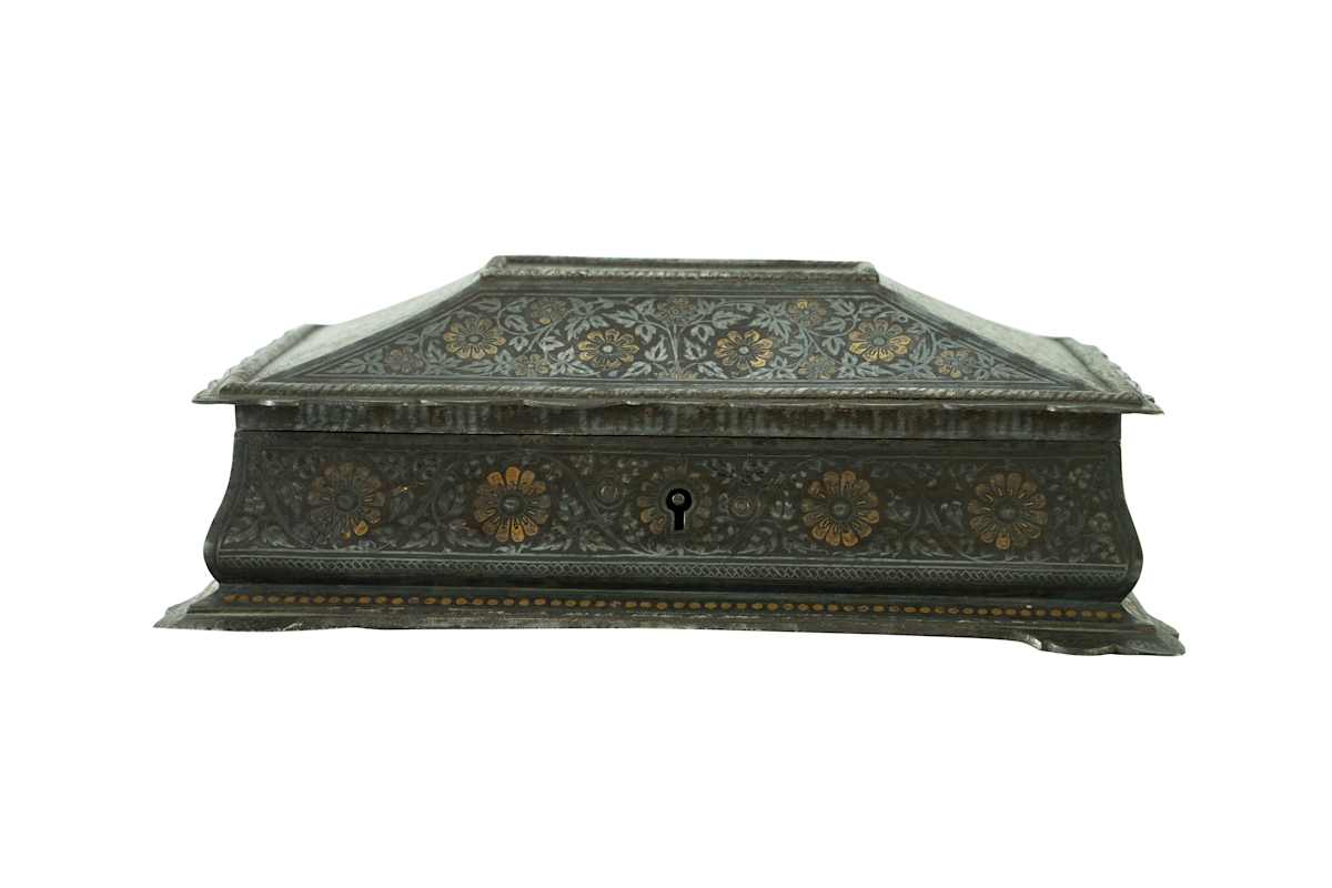 Trinket Box  Image: Rectangular trinket box adorned with intricate gold koftgari floral motifs on all sides and a sloped lid, resting on stylized feet; lined with red velvet, it blends opulent exterior with understated interior elegance.)