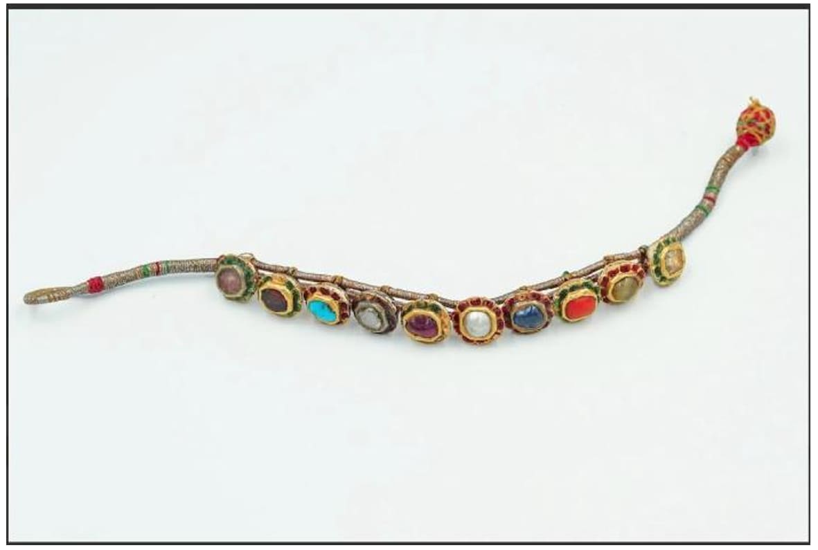 Navaratna Bracelet  Image: This gold bracelet unites nine auspicious gemstones symbolizing the planets. Enhanced with enamel accents and floral settings, it was worn as a talisman for protection, balance, and cosmic harmony.
