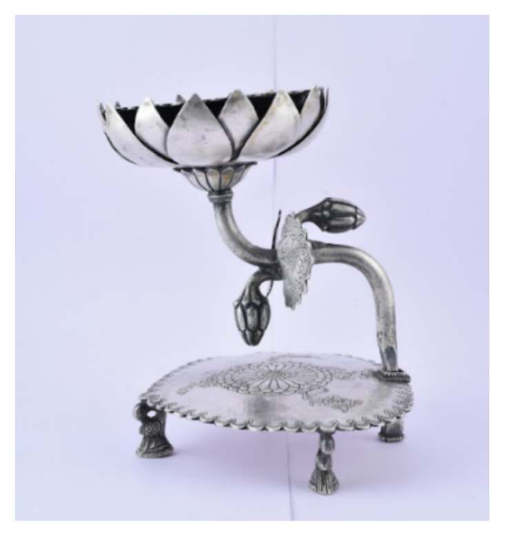 Silver Candle stand  Image: Silver candle stand in the form of a blooming lotus, with bud-laden stem, embossed medallion, and floral base on clawed feet.