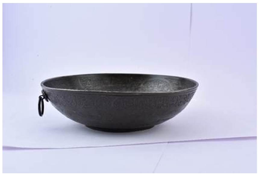 Talismanic bowl  Image: Bronze talismanic bowl inscribed with Quranic verses, used in healing rituals across the Islamic world. Etched with circular bands of calligraphy and radiating motifs; a ring handle suggests suspension. (cf. V&A 779-1889)