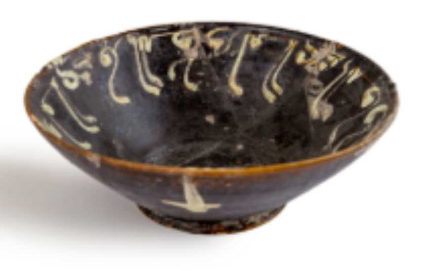 Bowl  Image: Rare and unusual earthenware bowl with floriated kufic script in cream slip on dark ground. Typical high foot and flaring sides, surface wear consistent with age.