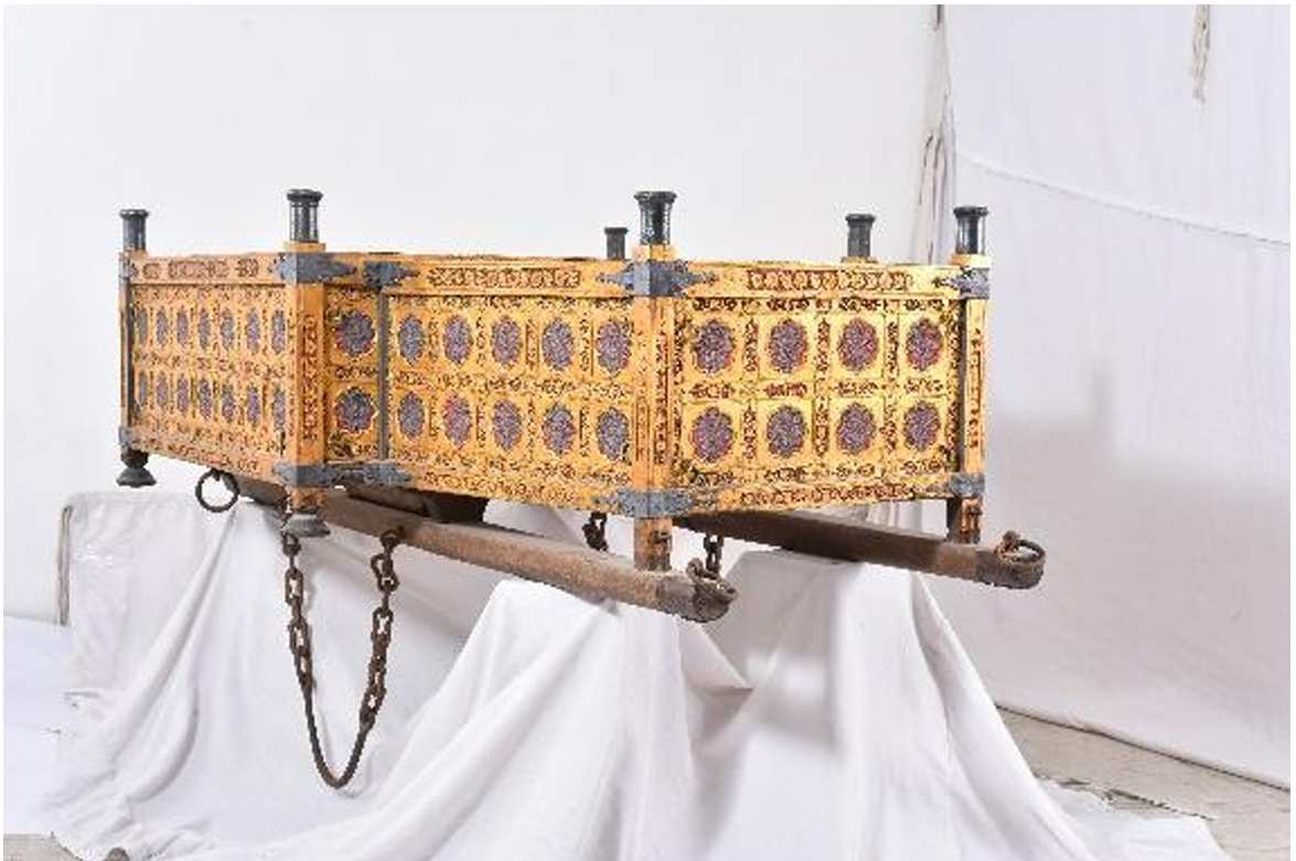 Saddle (Howdah)  Image: A moving throne of regal splendor, this magnificent ceremonial howdah, commissioned by a Deccan ruler, combines majestic design with Deccani artistry. Its wooden frame is clad in gilded copper and silver plaques, featuring Mughal lattice-and-flower patterns, blue-accented blossoms, and red backgrounds echoing Deccan architecture, including Bibi ka Maqbara and Golconda Fort. The dual seating, high protective sides, and metal legs with securing loops reflect both function and grandeur. The design closely relates to a 17th-century writing box (Metropolitan Museum of Art, 1998.434), as discussed in Sultans of Deccan India, 1500–1700: Opulence and Fantasy.

