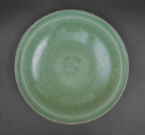 Longquan Celadon 'Peony' Charger  Image: Robustly potted with a carved central peony and fluted cavetto, this large sea-green glazed charger exemplifies classic Longquan ware, with an iunglazed ring on the base.