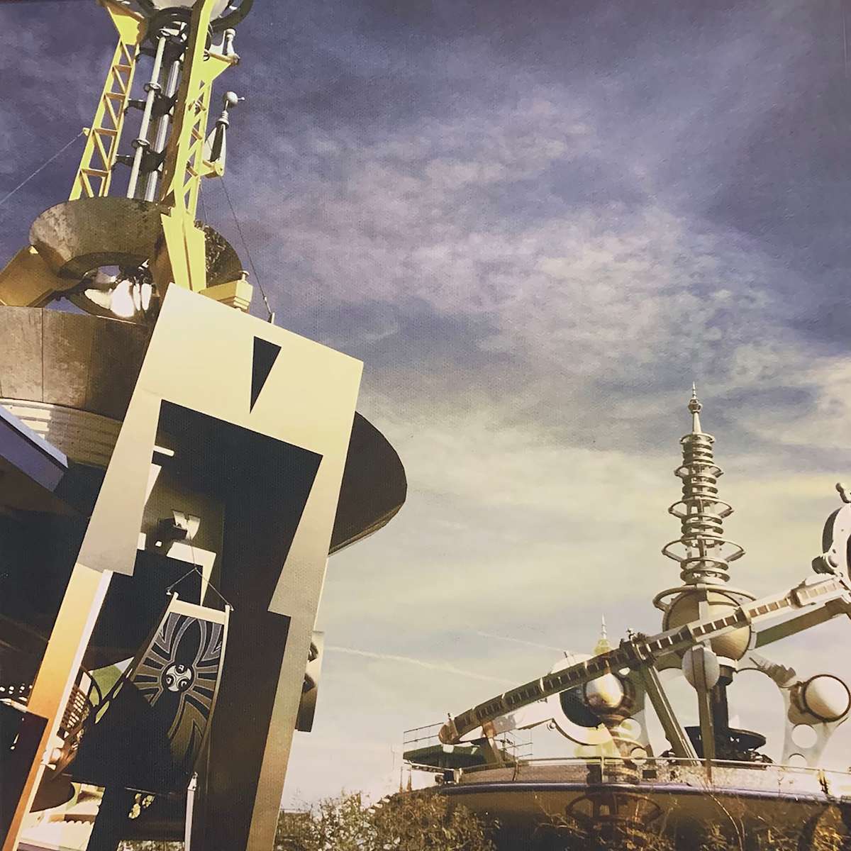 Tomorrowland 3 by Sherry Ross  Image: As a kid, my favorite land at Disneyland was always Tomorrowland. What could beat Space Mountain in the heart of a nerdy middle school tween? For me, it was a gateway to a magical world of science fiction wonder. Tomorrowland had all the best rides and carried with it that funky late-sixties vision of the future.

As I grew older, the space-age future I once marveled at transformed into something else—a retro vision of what once was, dated yet still endlessly fun. When I finally had the chance to take my own kids, I loved being able to share not only the rides, but also the charm of that vintage, imagined future.

Two of Tomorrowland’s most iconic rides are captured in this image. Their sleek, futuristic forms—now carrying a distinctly retro feel—stand out against a dramatic sky. The muted metallic tones heighten that sense of vintage futurism, evoking both the optimism of imagined worlds to come and the nostalgia of memories past.