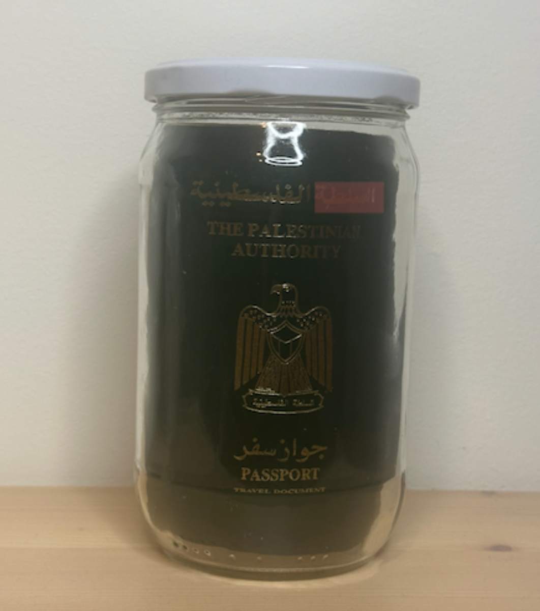Homo Sacer by Dr. AbdalHadi Alijila  Image: Inside a glass jar, a real passport issued by the Palestinian Authority is sealed. Typically, a passport grants freedom of movement and recognition, but in this piece, it's transformed into an object preserved, sealed, and silenced within a tightly sealed jar.