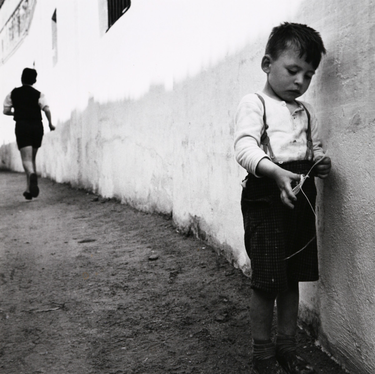 Seville, Spain by Edward R. Miller  Image: Two white children by a white wall, one in the background running away