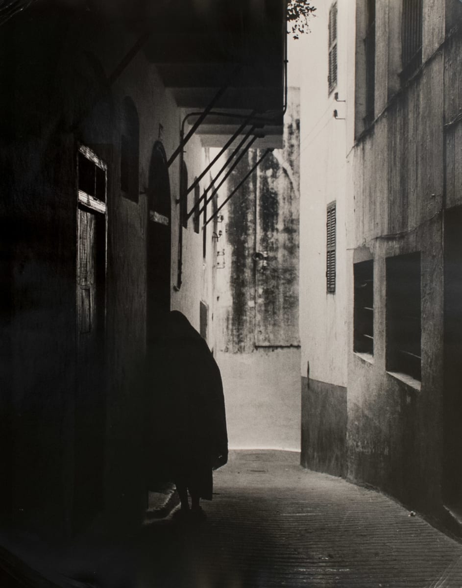 Fez, Morocco May 1962 by Edward R. Miller  Image: Narrow alley with dark clad figure in doorway.
