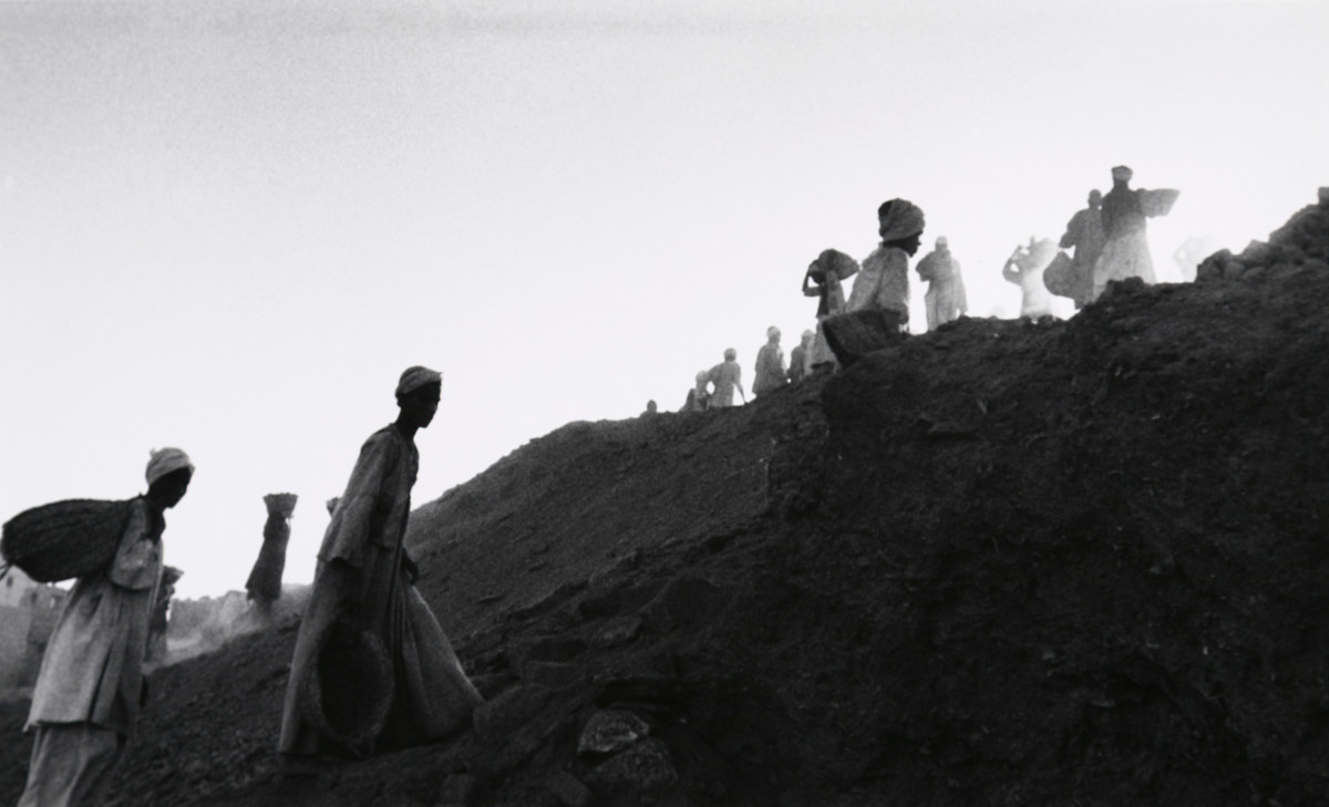 Karnak, Egypt 1956 by Edward R. Miller  Image: Egyptian people in traditional long robes carrying baskets up hillside