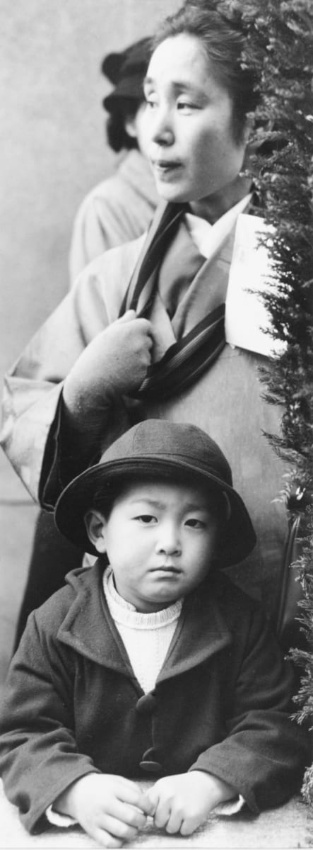 Tokyo, Japan 1948 by Edward R. Miller  Image: A portrait of two Japanese people, one an adult and one a child, the child sits in front of the adult and looks directly into camera.