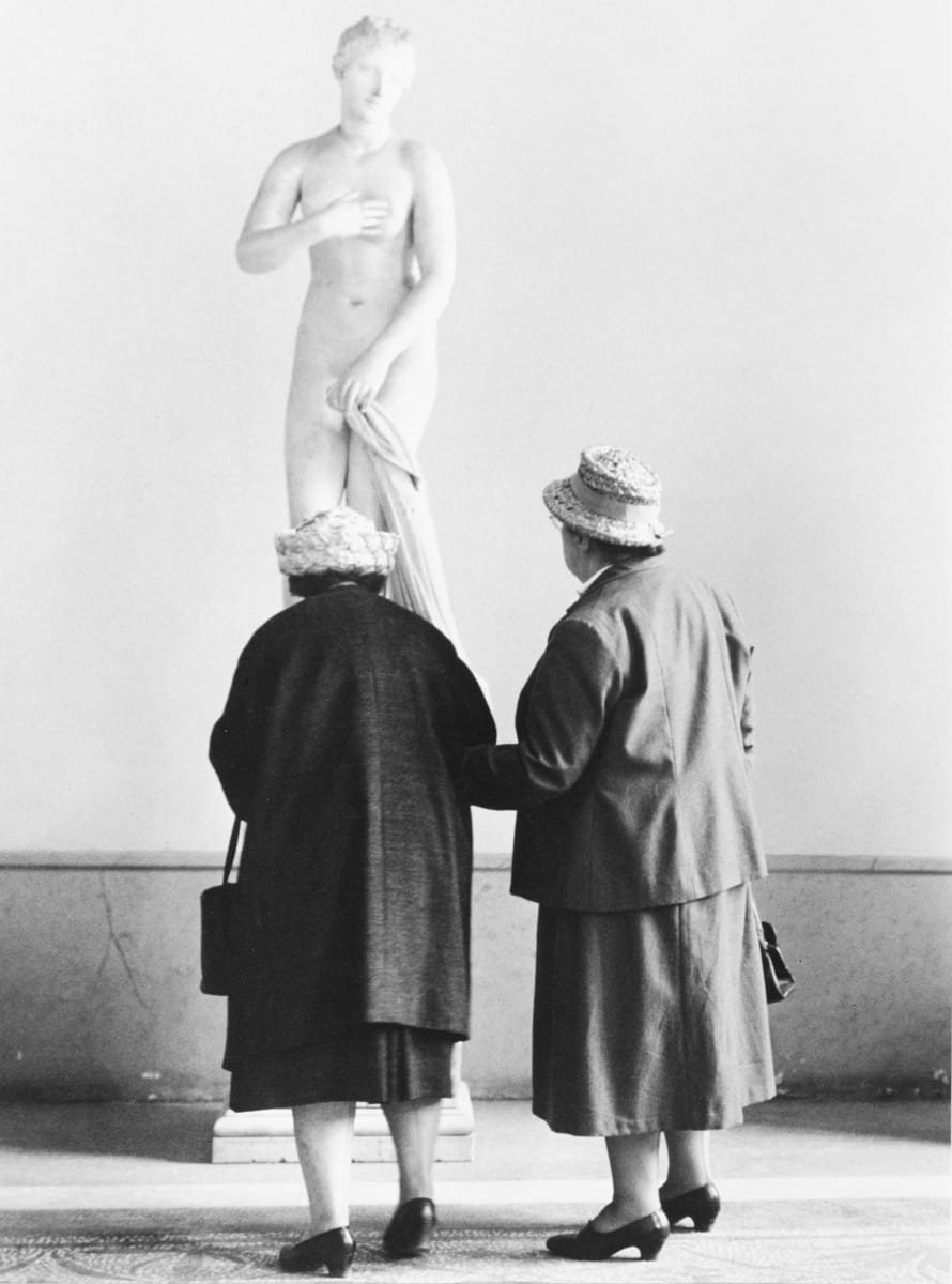 Rome, Italy 1962 by Edward R. Miller  Image: Two elderly people in skirts with straw hats looking at a statue of Venus with their backs to the camera