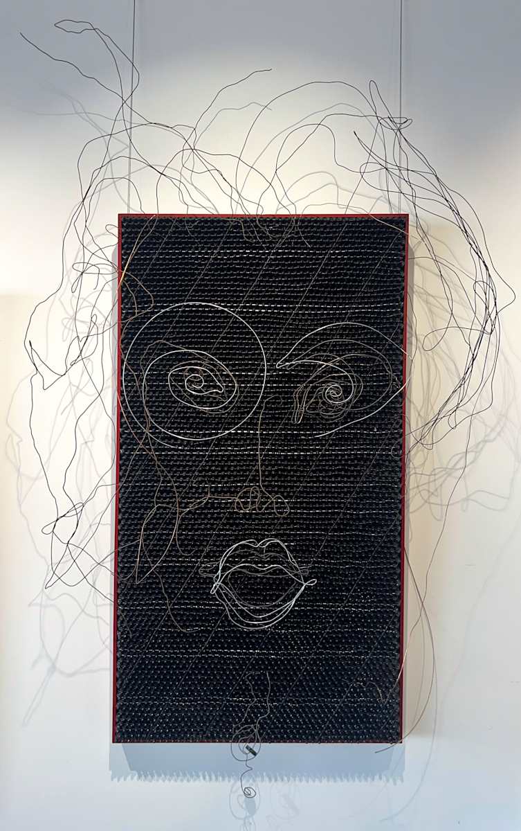 "J" Wired by John McCaskill  Image: In this work, the act of drawing becomes sculptural. Instead of working on paper, the “line” rises into space, gaining dimension, shadow, and tension. The tactile grid of black end caps grounds the piece, while the wire delineation invites viewers to see a face both emerging from and dissolving into the surrounding atmosphere. “J Wired” reflects my ongoing interest in structure versus spontaneity, and how simple materials can be transformed into something alive and emotive.