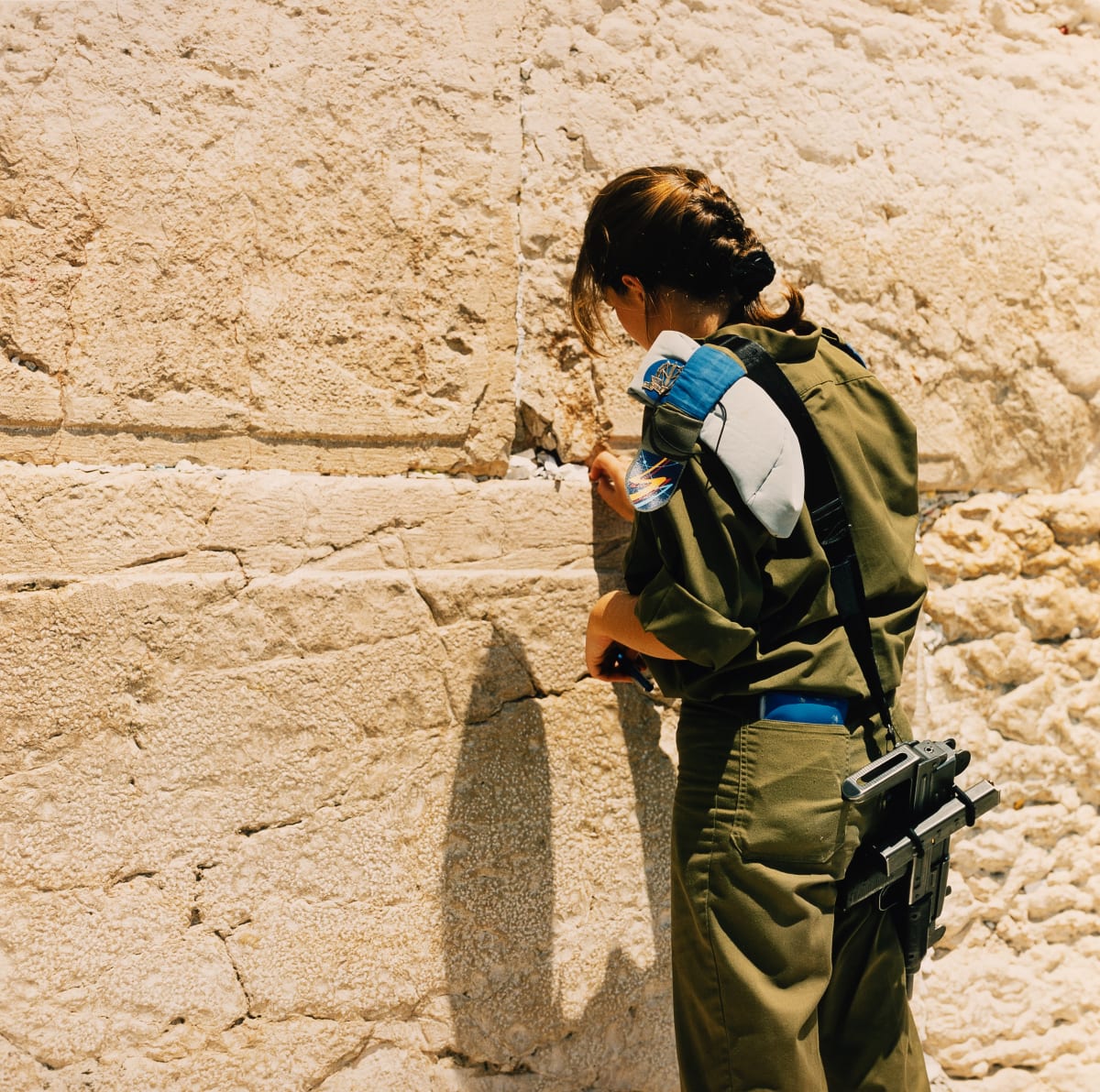 Soldier Putting Prayer into Cracks of the Western Wall (Jerusalem, Israel) by Amie Potsic 