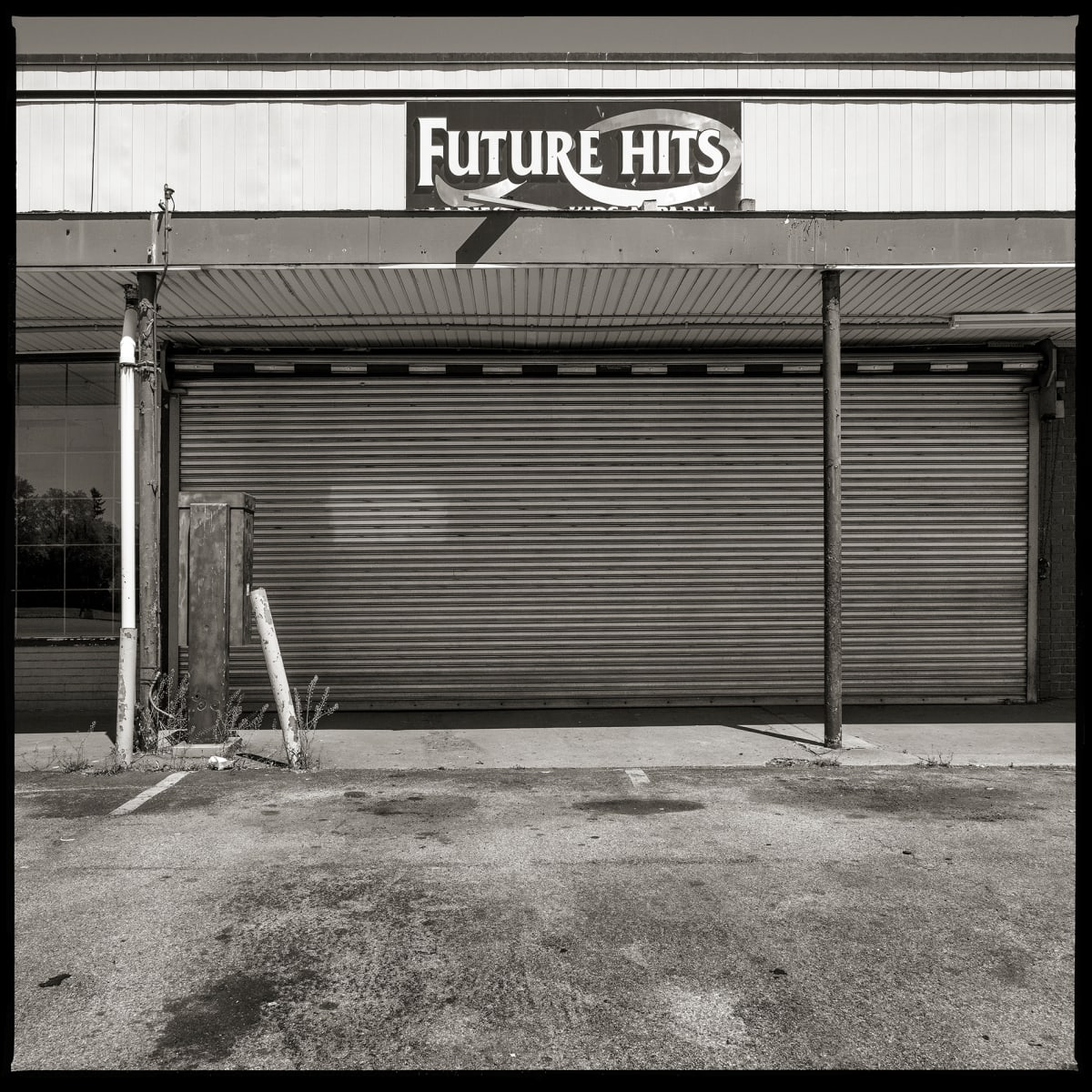 585.288.9600 – 836 North Goodman Street, Rochester, NY 14609 by Eric T. Kunsman  Image: ID: A black and white image shows a closed building.  The awning has a "Future Hits" sign.  There is a payphone booth standing next to a pole in front of the building.