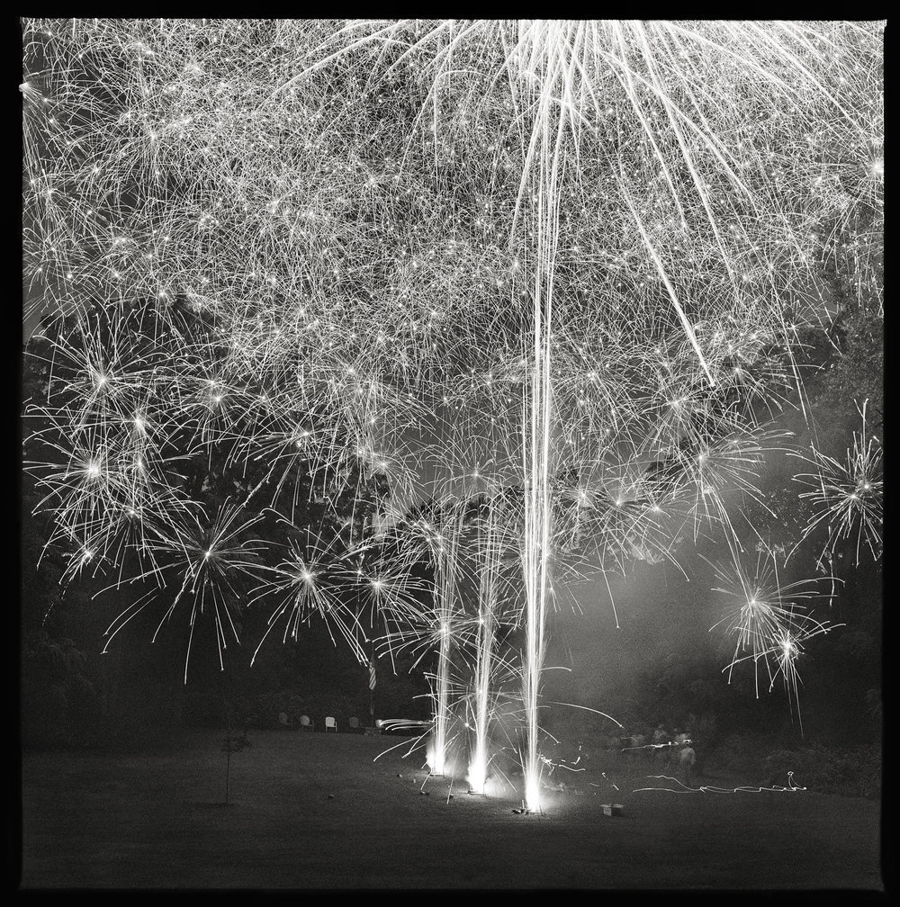 July 4th, 2014- Palmyra, NY by Eric T. Kunsman  Image: ID: A black and white image shows three streams of fireworks going off at night.