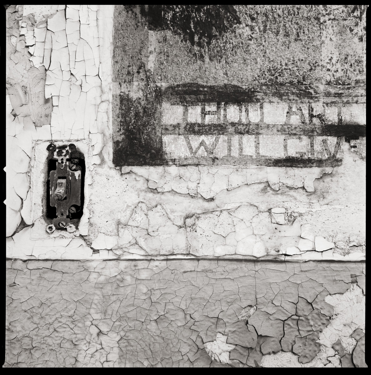Thou Art…, Will Give… by Eric T. Kunsman  Image: ID: A black and white image shows a close up of a wall. There is a light switch in the left side of the wall and on the right it reads "Thou Art" "Will Give".  The wall itself has cracked paint and plaster.