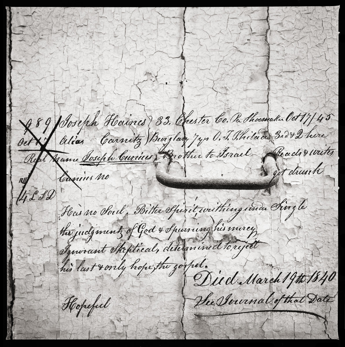 Joseph Haines by Eric T. Kunsman  Image: ID: A black and white image shows a wall with a handle mounted in it.  Overlaying the image is information about the former prisoner Joseph Haines.