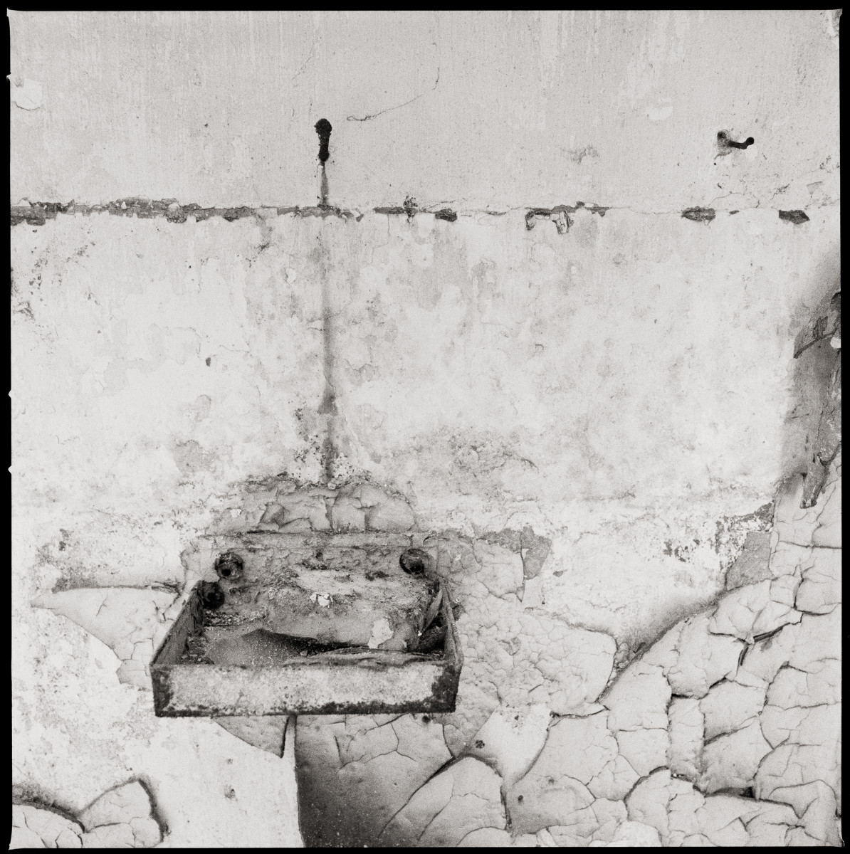 Soap Dish by Eric T. Kunsman  Image: ID: A black and white image shows a dirty metal soap dish that is mounted on a cement wall that is cracking.
