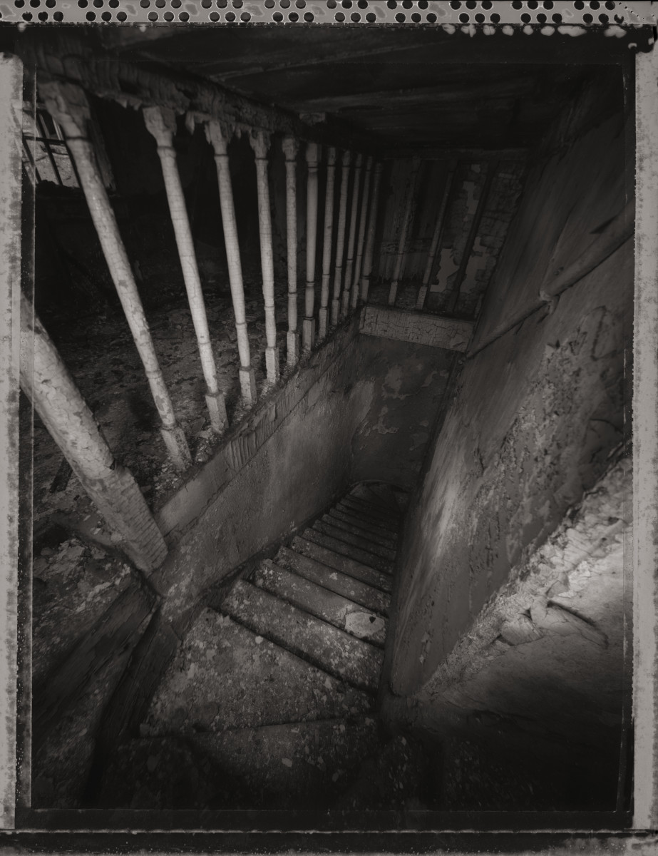 Incorrect Passage by Eric T. Kunsman  Image: ID: A black and white image shows a downward leading stairway that is dirty and covered in debris.  There is a railing at the top of the stairs on the left.  The bottom of the stairs in not visible.