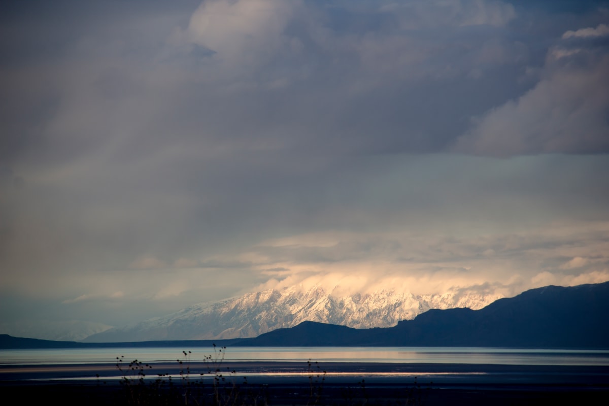 Fading Light by Nila Jane Autry  Image: Darkness all around, and then there are the snow capped mountains with evening sunlight beginning to fade...