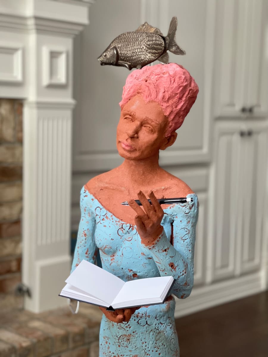 Flow by Adena  Helm Art  Image: Sculpture of standing woman holding a journal.  Wearing a blue dress and pink hair. And fish atop her head.  