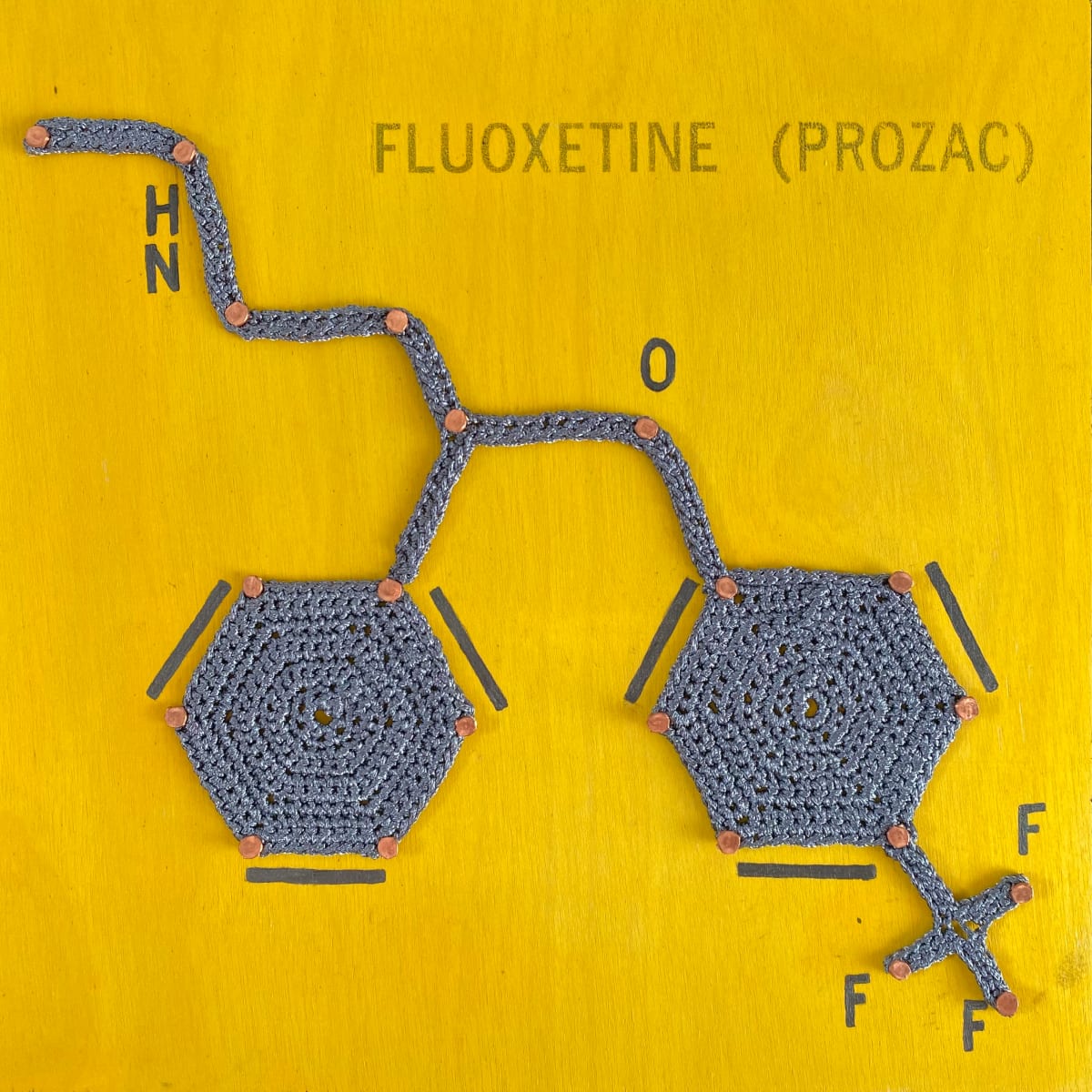 Take 'Em if You Need 'Em: Fluoxetine (Prozac)  Image: Part of the Balancing Act series highlighting how chemical prescriptions, behavioral therapies as well as art and crochet are methods to obtaining better mental and physical health. This piece focuses on the chemical element compound Prozac, used in the treatment of depression.