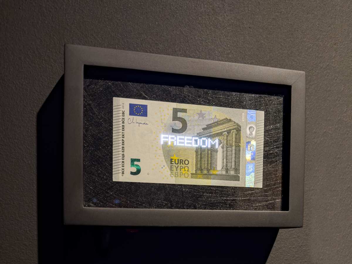 Planetary Values- 5 Euro Bill - Freedom by Jorge Luis Vaca Forero  Image: Planetary Values- 5  Euro Bill / (Freedom) is a unique approach to global politics. It focuses on the Euro bill, one of the main currencies in the world economy. This project highlights the most frequently mentioned values from the European Union’s Constitution by using laser cuttings to create perforations in the bills, which are then illuminated by LED lights.

The aim is to challenge the legitimacy and symbolic significance of the State. It does this by connecting the symbolism of money with the economy it represents and the values and commitments made by governments that are often not met around the world. The words on the bills can only be seen when illuminated, emphasizing their hidden nature.

This initiative turns these bills into seemingly useless objects and invites us to reconsider the global significance of currency. It questions the ideals of peace, well-being, and democracy that nations claim to uphold for their citizens, suggesting that these ideals may not be fully realized and are limited by the currency that represents economic and social exchanges.
