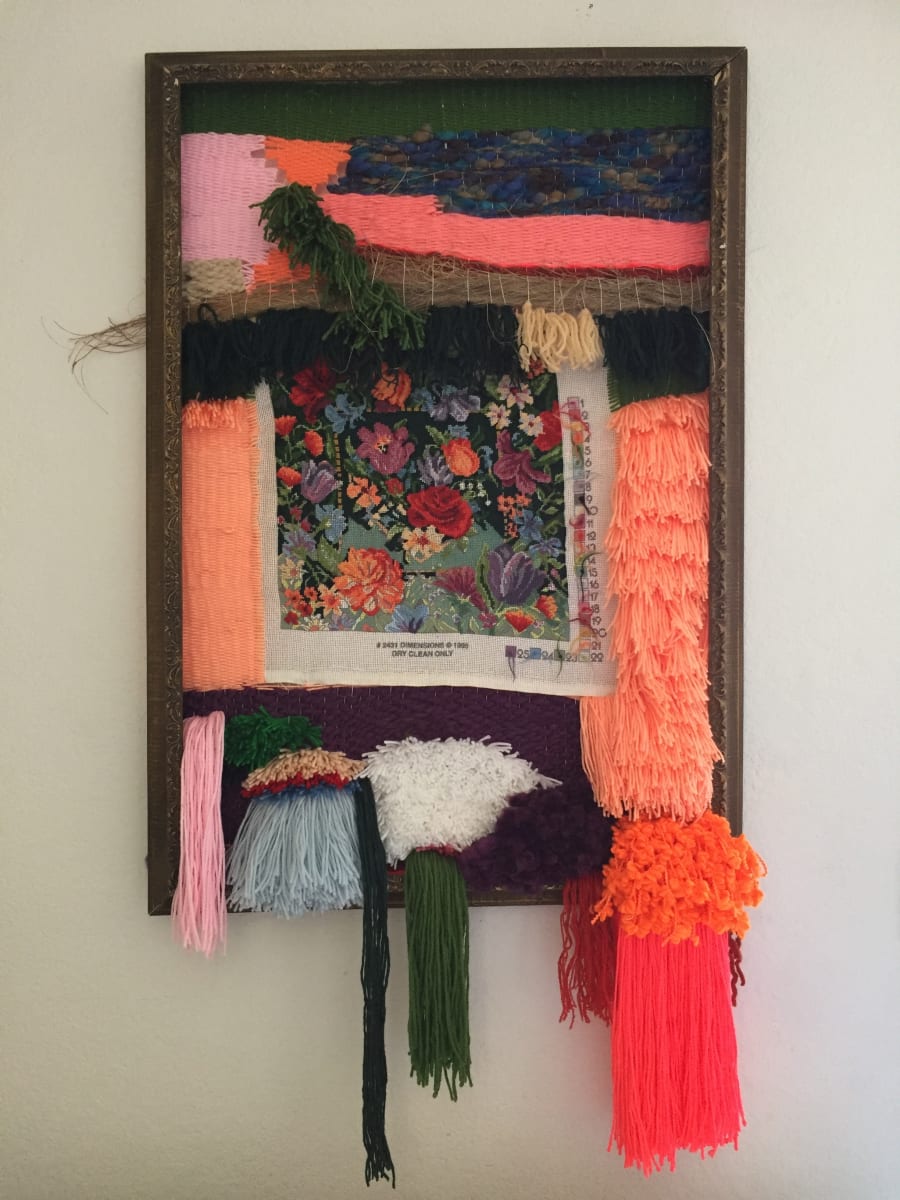 Unfinished Business by Katie Ruiz  Image: This embroidery was purchased at an estate sale of a person who had passed away. The embroidery is unfinished so  I decided to complete it in my own way be weaving the embroidery into a frame loom and adding tassels. 