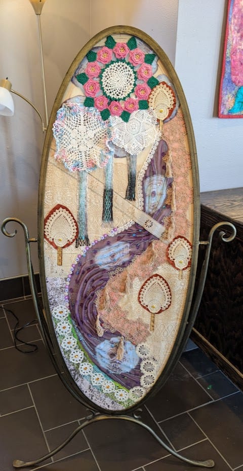 Landscape in Lace by Marjorie  Cutting  Image: Tapestry; Made of different laces, doilies, sheer fabrics, and bead embellishments. The piece is set in an old mirror frame.