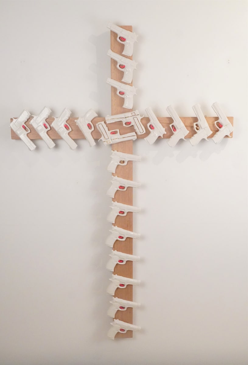 In God We Trust by annekwasner@gmail.com  Image: Wooden cross with porcelain white guns attached with bright pink triggers on them. 