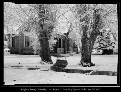 [George Beard's Home and Studio in Coalville] by George Beard  Image: Two large trees line a sidewalk leading to a brick house covered in snow.
