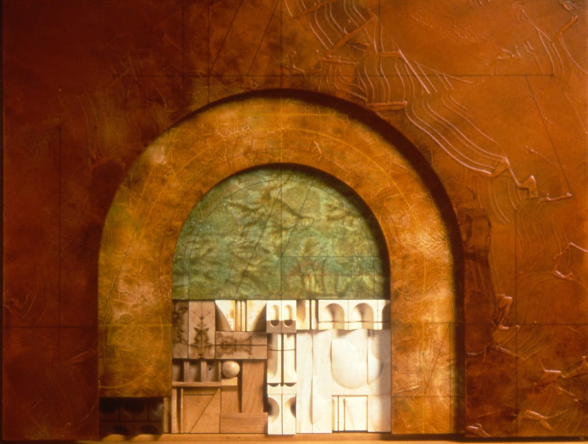 Untitled Construction #388 by Abe Ajay  Image: Alt Text Long Description: A mixed-media artwork featuring a large arch embedded within a rectangular canvas. The backdrop is a textured, reddish-brown surface, displaying abstract line patterns and various sculptural elements. Inside the arch, a gradient of muted green colors fills the inner semicircle, providing a contrasting background. At the bottom of the arch, geometric shapes in a palette of white, cream, and light brown form a structured, architectural design. These shapes include rectangles, circles, and arches, creating a sense of depth and dimension.  Note: the alt text was written with support from the ASU Image Accessibility Creator AI tool.