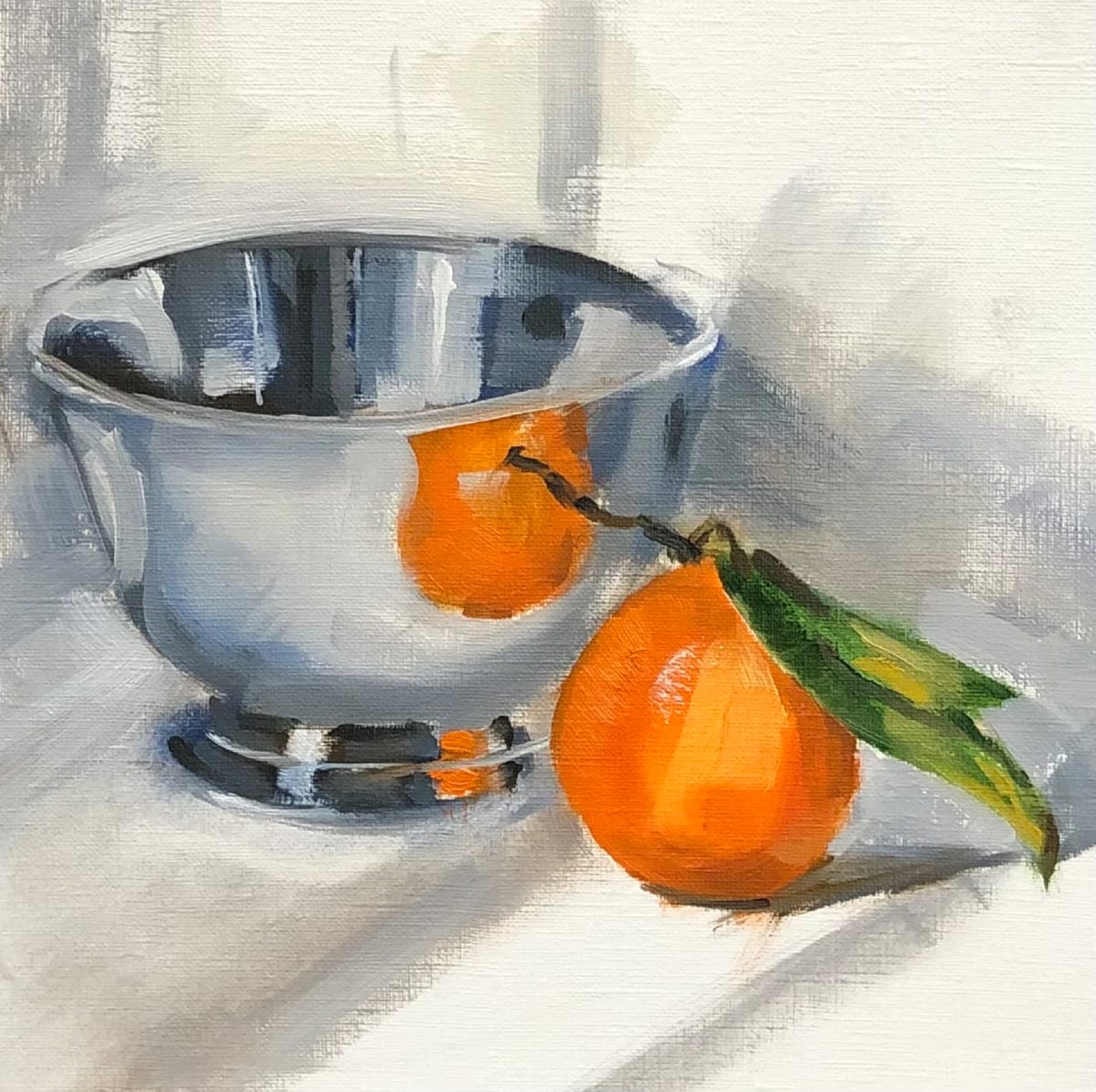 Silver with Orange by Cary Galbraith  Image: A sterling silver bowl beside a tangelo with stem and leaf still attached. The orange is reflected in the bowl 