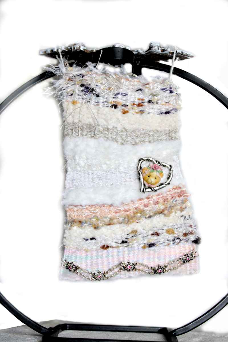 Vintage Dreams Mini Art Tapestry by Annette  Image: Sweet vintage jewelry heart bear on a special hand woven tapestry using chenille, popcorn fur, cotton string, linen, feather, ladder and schimmery string yarns found at local thrift supporting the intellectually & developmentally challenged 