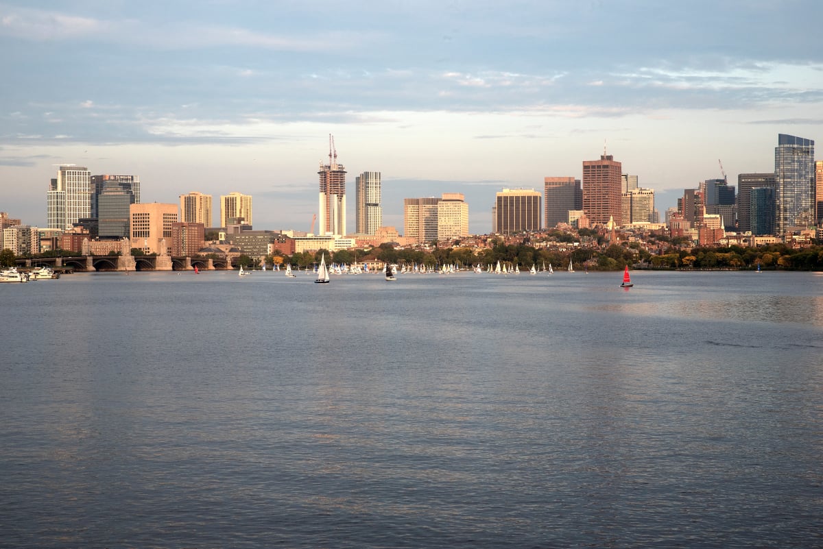 Boston Skyline-1 by Sanjay Marathe  Image: The evening sunlight falls on the Boston skyline. A gentle breeze powers the sailboats and makes gentle ripples on the Charles river. I made this shot while walking on the bridge at Cambridge, as joggers ran past enjoying the beautiful day.