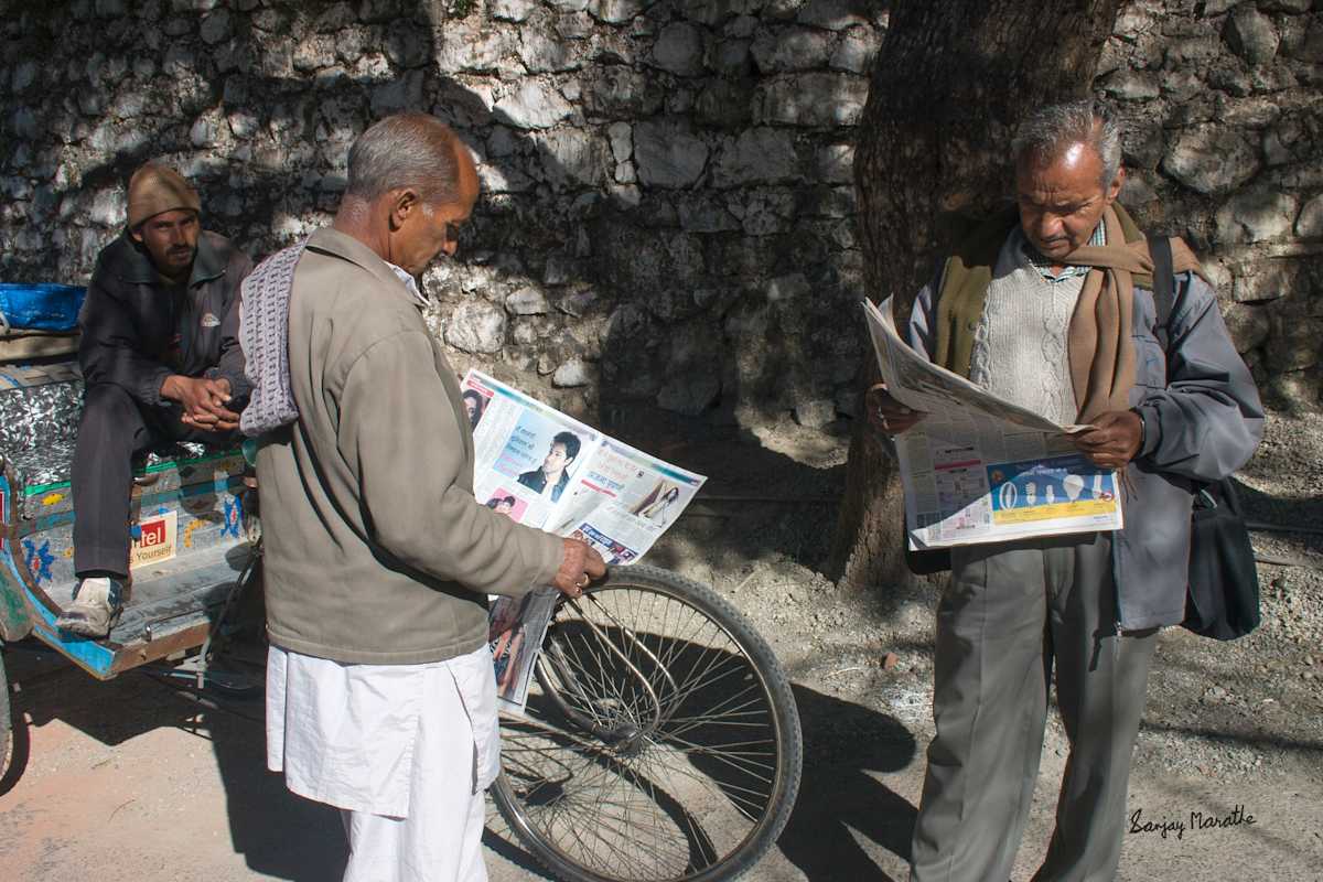 Shared Headlines-1 (2005) by Sanjay Marathe  Image: I took this photograph on a winter morning in Mussoorie, Uttarakhand. The two men stood at a rickshaw stand on the Mall Road, engrossed in their newspaper. Rather than waiting for a ride, they seemed to be simply enjoying a sunny respite from the winter cold.