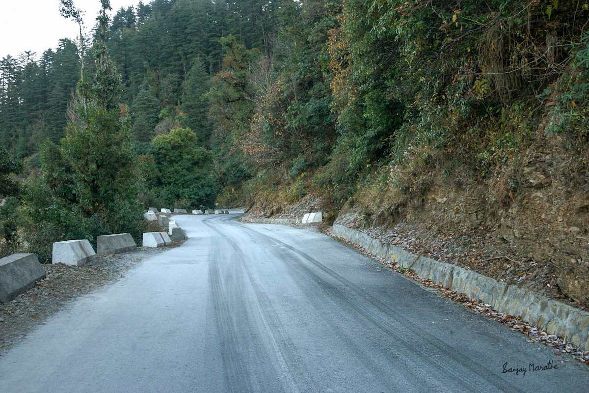 Icy Pass, Dhanolti, Uttarakhand (2005) by Sanjay Marathe  Image: On a freezing winter morning in Dhanolti, Uttarakhand, India, I set out to explore the landscape. The intense cold had turned the morning dew into a thin layer of ice on the road, causing our car to skid and swerve. I decided to stop and capture the moment, as the vibrant green trees stood in striking contrast against the frost-covered road.