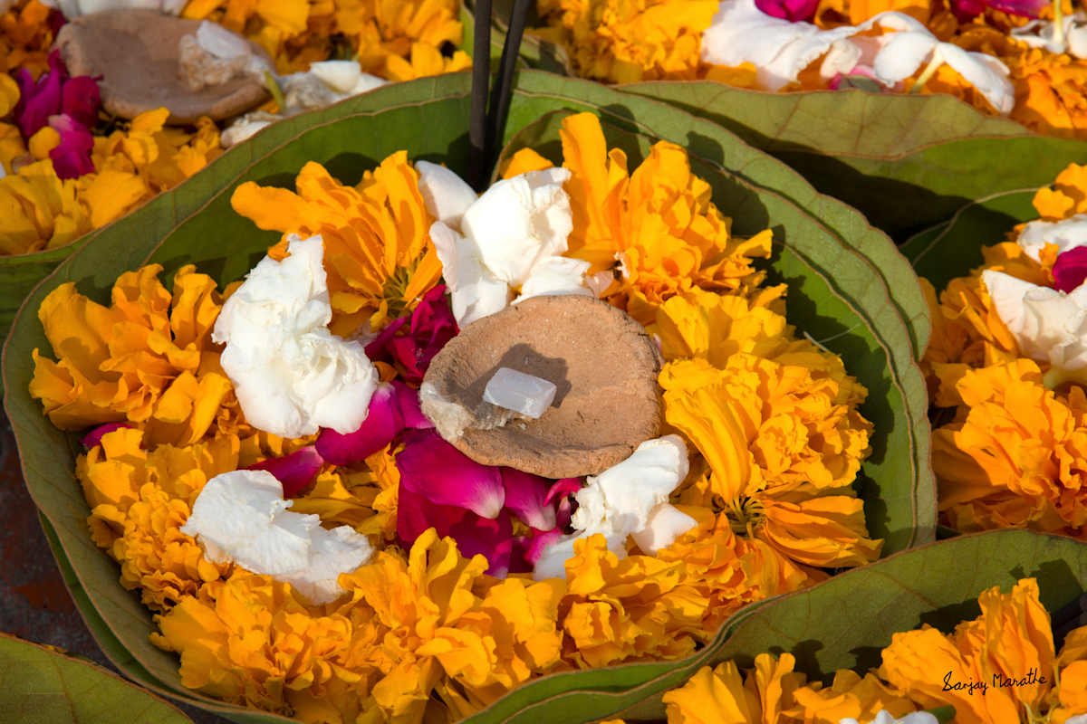 Flowers And Lamp, Haridwar (2013) by Sanjay Marathe  Image: Small baskets on a street cart in Haridwar, Uttarakhand, India, filled with flower petals and an earthen lamp, ready for pilgrims to offer to the river Ganges.