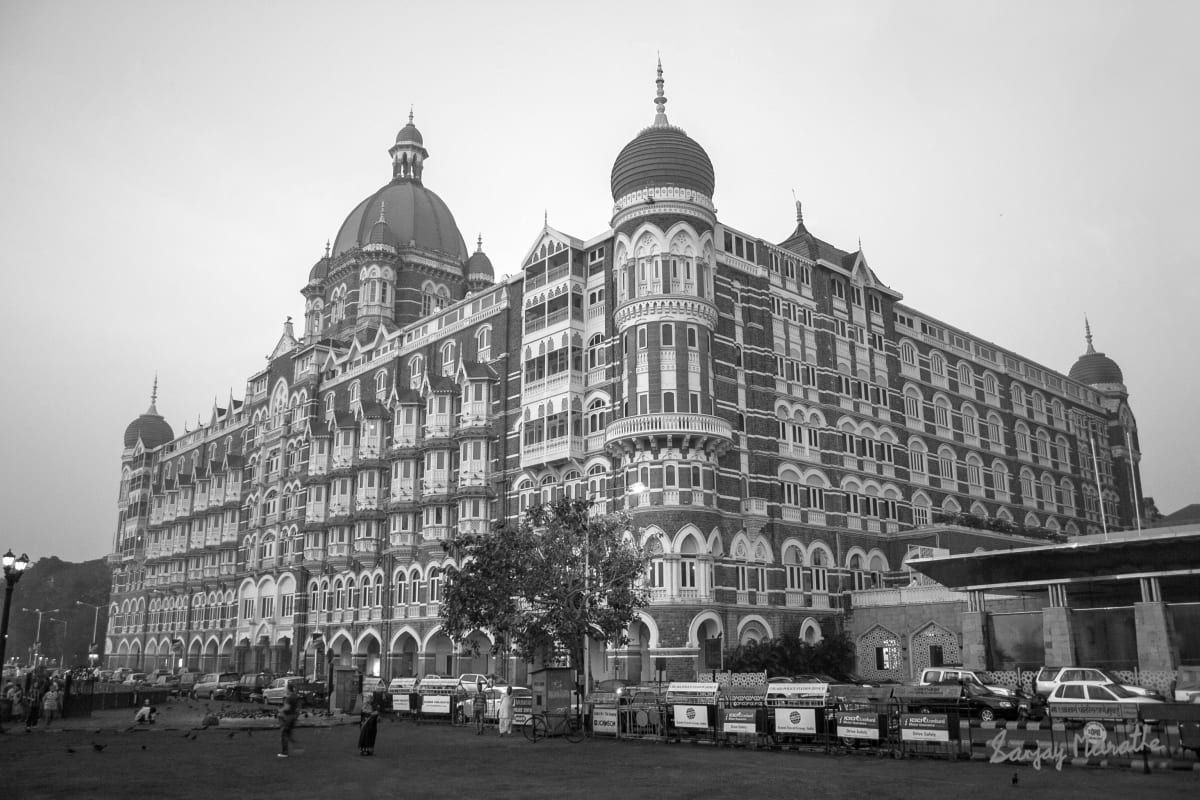 Taj Palace At Dawn (Black & White) (2007) by Sanjay Marathe  Image: This is a black and white photograph of the old wing of Taj Mahal Palace hotel in Mumbai. It depicts the grand building in all glory. I photographed it at dawn, with a hint of pink still visible in the sky. There are no distractions in the foreground, which gets quite crowded during the day.

The Taj Mahal Palace hotel welcomed the first 17 guests on 16 December 1903. It offered 30 private suites cum apartments and 350 double and single rooms, with the best in luxury and technology. It was patronised by Europeans, Indian Maharajahs and Princes and other elite gentry. During the freedom movement and when India gained independence, it also hosted luminaries like Mohamed Ali Jinnah, Sarojini Naidu, Mohandas K Gandhi and Jawaharlal Nehru, and foreign visitors Aldous Huxley and Somerset Maugham who were supportive of the movement.