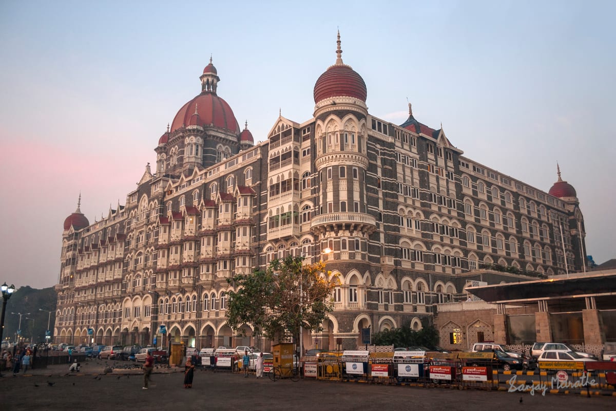 Taj Palace At Dawn (2007) by Sanjay Marathe  Image: This is a photograph of the old wing of Taj Mahal Palace hotel in Mumbai. It depicts the grand building in all glory. I photographed it at dawn, with a hint of pink still visible in the sky. There are no distractions in the foreground, which gets quite crowded during the day.

The Taj Mahal Palace hotel welcomed the first 17 guests on 16 December 1903. It offered 30 private suites cum apartments and 350 double and single rooms, with the best in luxury and technology. It was patronised by Europeans, Indian Maharajahs and Princes and other elite gentry. During the freedom movement and when India gained independence, it also hosted luminaries like Mohamed Ali Jinnah, Sarojini Naidu, Mohandas K Gandhi and Jawaharlal Nehru, and foreign visitors Aldous Huxley and Somerset Maugham who were supportive of the movement.