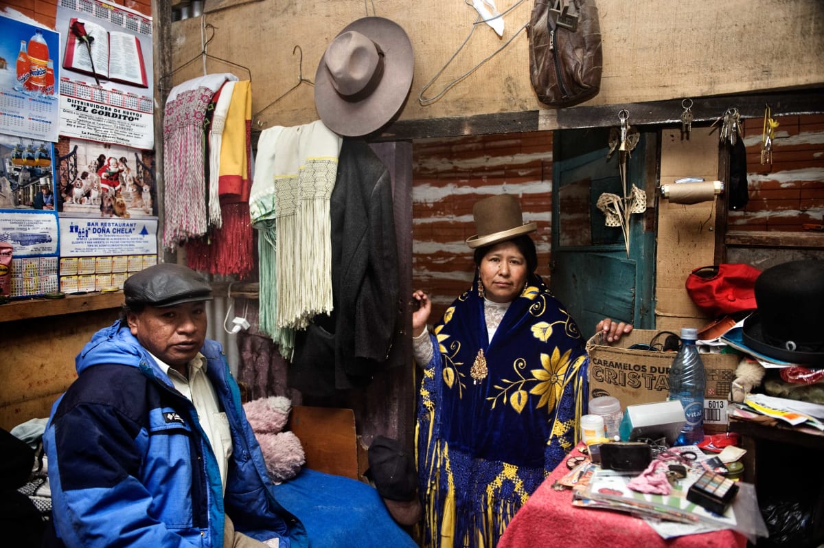 Untitled  Image: Carmen Rosa wearing an embroidered mantle and her bowler hat inside a shop.