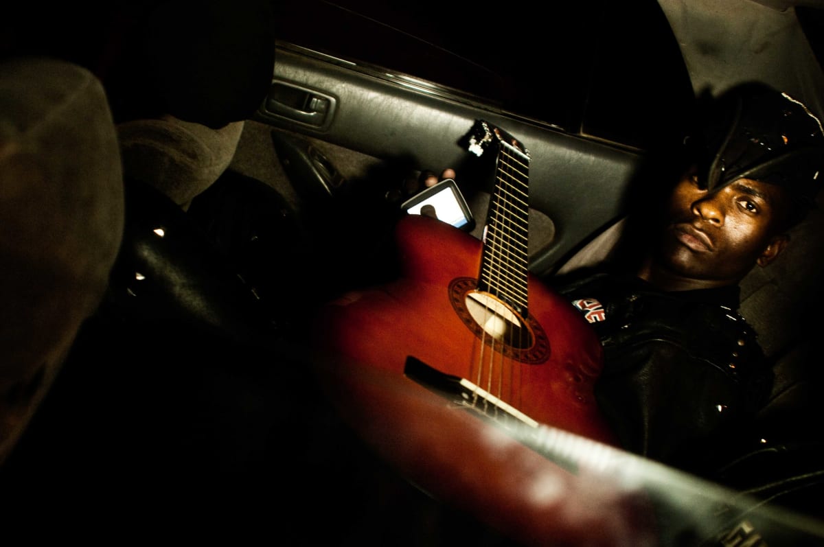 Untitled  Image: A guitarist in the back of a car.