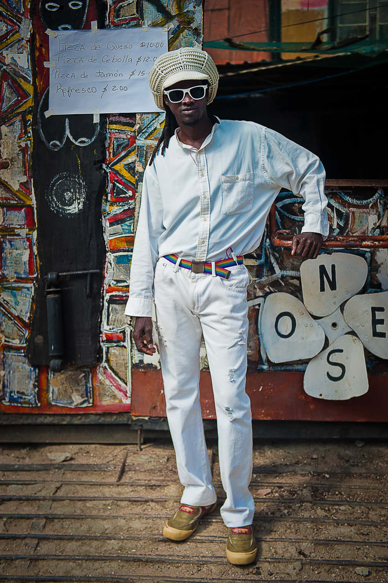 Untitled (ONES)  Image: Young man posing in front of a food kiosk.