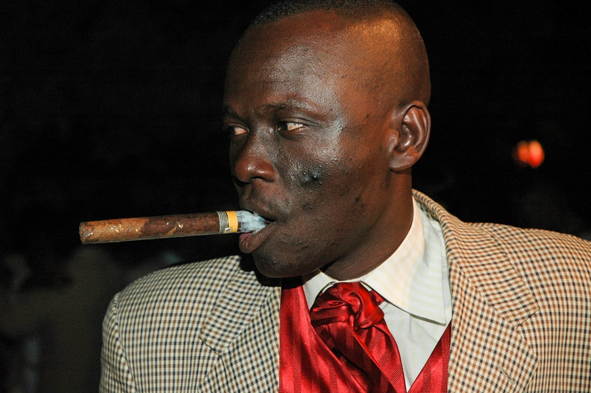 Untitled  Image: Sapeur in tartan suit and red gilet with an unlit cigar in his mouth. Brazzaville, Congo (2007)