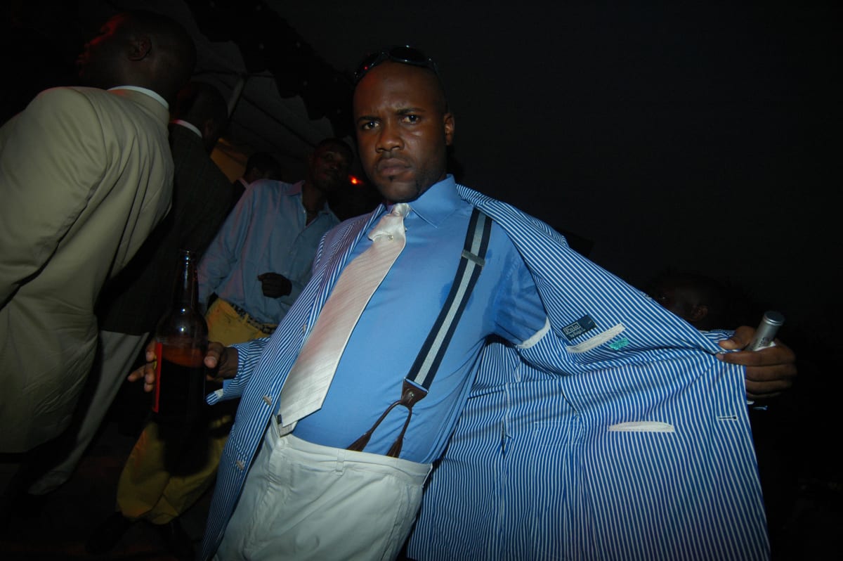 Untitled  Image: Man showing his bracers, opening his blue and white pinstriped jacket, at the nightclub Main Bleu. Brazzaville, Congo (2007)