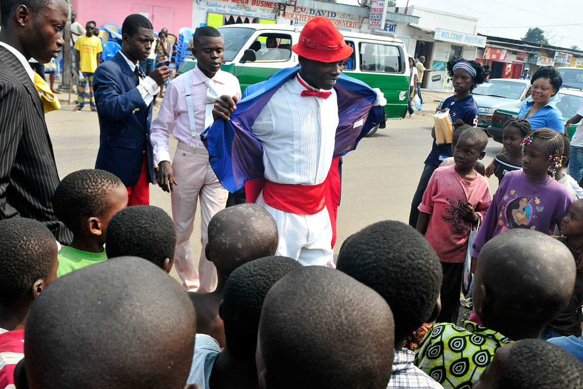 Untitled (Vive la Sape #7) by Daniele Tamagni Foundation  Image: Young Sapeur showing off his outfit to a group of kids on  the streets of Brazzaville, Congo (2008)